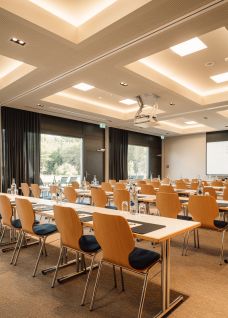 Ein geräumiger, lichtdurchfluteter Seminarraum mit moderner Ausstattung. Die grossen Fenster bieten einen Blick ins Grüne, während helle Holzmöbel und flexible Sitzgelegenheiten ideale Bedingungen für Meetings und Konferenzen schaffen. Die Raumgestaltung ist einladend und fördert konzentriertes Arbeiten in angenehmer Atmosphäre. ©Deltapark Moderner Seminarraum mit Tageslicht