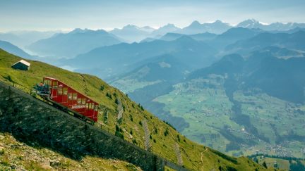 Niesenbahn am steilen Berghang; im Hintergrund weite Alpentäler und Gipfel – inspirierende Kulisse für Incentives und Meetings in der Thunersee-Region. @Niesen Standseilbahn am Hang mit Weitblick über die Schweizer Alpen bei Thun