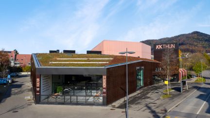 Aussenansicht des KKThun in Thun, Kanton Bern – ein moderner Veranstaltungsort für Meetings, Kongresse und Firmenanlässe. Das Gebäude mit begrüntem Dach und großen Glasflächen liegt verkehrsgünstig, umgeben von Bergen und urbaner Infrastruktur. Ideal für nationale und internationale Geschäftsevents. @KKThun Moderne Kongresshalle KKThun Aussenansicht